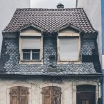 Small aged and old house between two modern and new houses