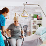 Old disabled lady walking with the help of crutches in nursing home